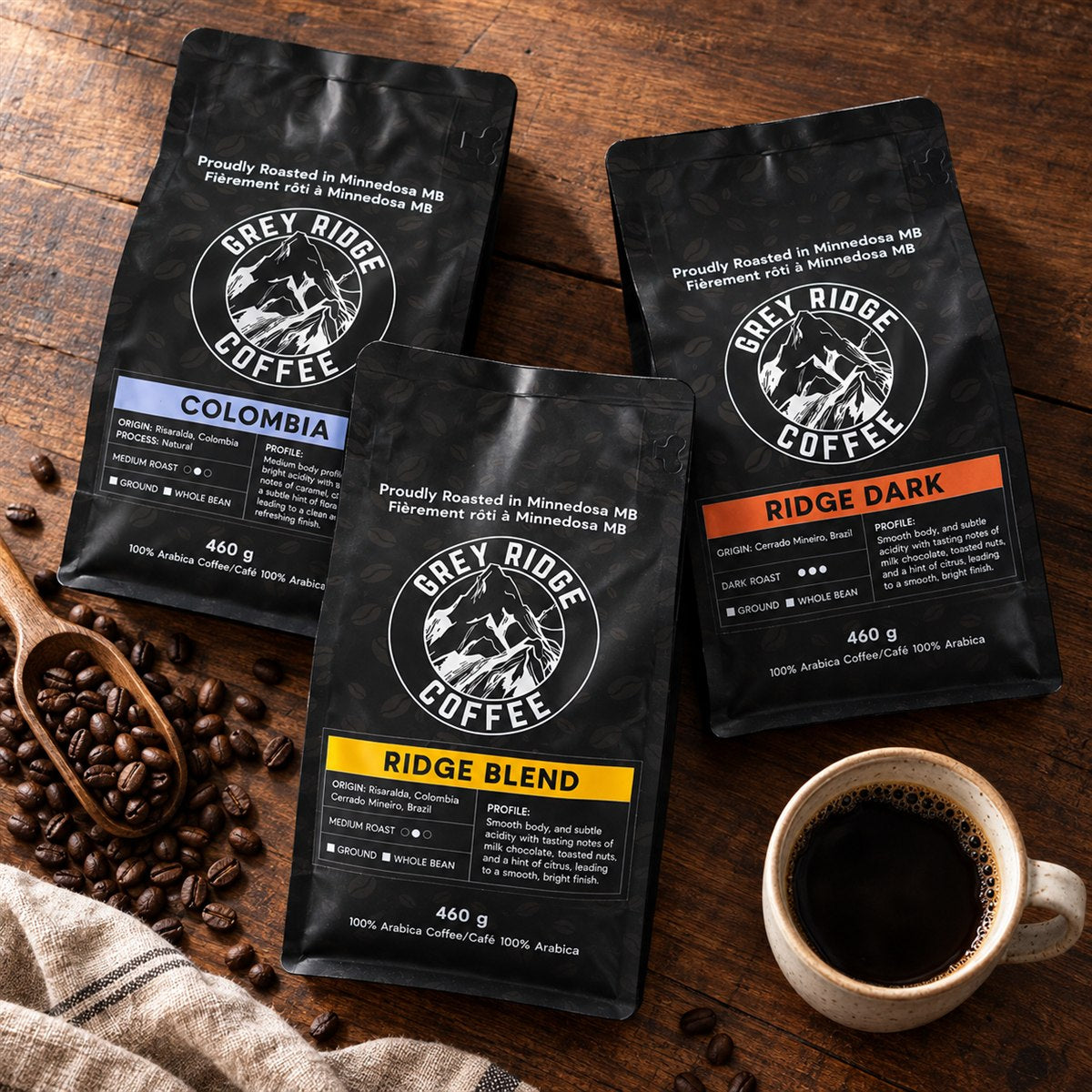Grey Ridge Colombia, Ridge Blend and Ridge Dark coffee bags arranged on a wooden table with coffee and beans.
